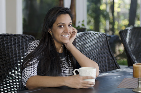 Pretty Indian woman relaxing as she drinks her teaの写真素材
