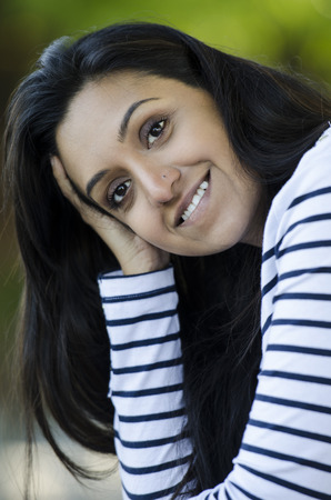 Very pretty Indian girl smiling and happy as she looks at the cameraの写真素材