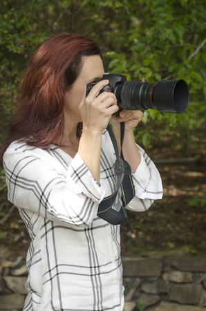 Landscape photographer aiming at her subject outdoorsの写真素材