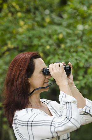 pretty lady in the woods watching for birdsの写真素材