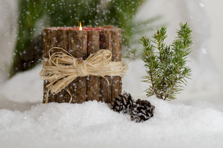 Christmas candle burning in the falling snowの写真素材