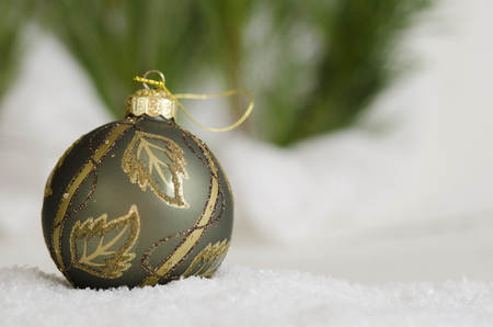 Green and gold ornament in the snowの写真素材