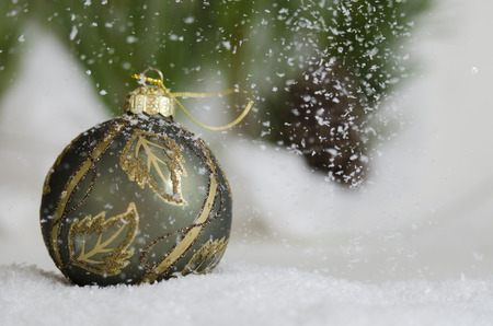 Green and gold ornament in the snow fallの写真素材