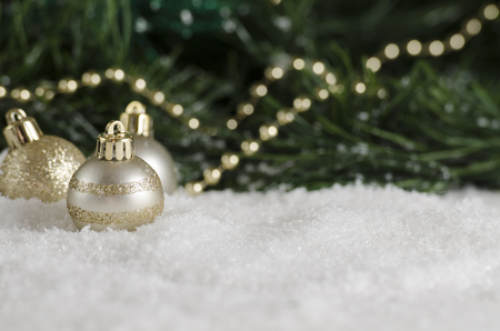 golden ornaments in the snow by the treeの写真素材