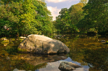 Still Rocky Tree Shaded River with Reflectionsの写真素材