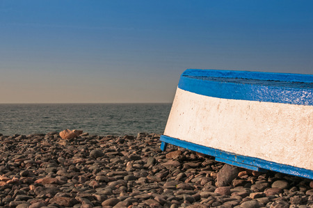 Upturned Fishing Boat on Pebble Beachの写真素材