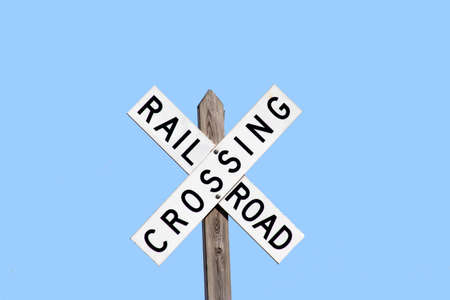 railroad crossing sign with a bright blue skyの写真素材