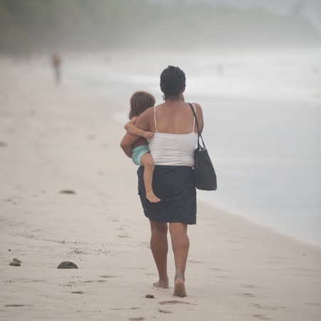 Woman carrying a child on the shoreline in Costa Ricaの写真素材