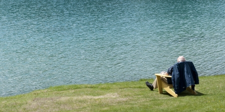 Senior man sitting on a chair at the lakeside, Beauvert Lake, Jasper National Park, Alberta, Canadaの写真素材