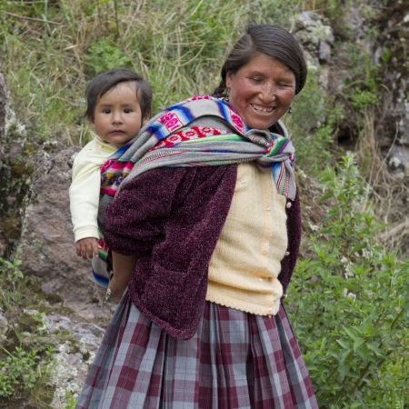 Woman carrying her son on back and smiling, Pisac, Sacred Valley, Cusco Region, Peruのeditorial素材