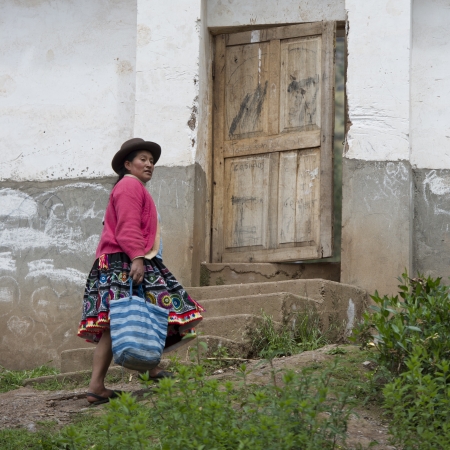 Quechua Indian woman walking towards the entrance of Chumpepoke Primary School, Poques, Sacred Valley, Cusco Region, Peruのeditorial素材