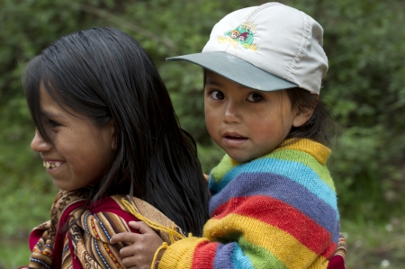 Girl giving piggyback to her sister and smiling, Sacred Valley, Cusco Region, Peruのeditorial素材