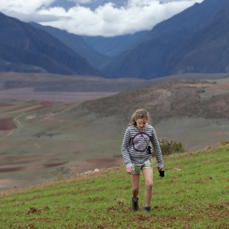 Teenage girl walking in a field with Sacred Valley in the background, Cusco Region, Peruのeditorial素材