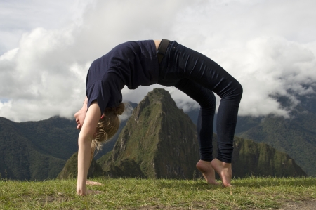 Teenage girl doing wheel pose with valley in the background, The Lost City of The Incas, Machu Picchu, Cusco Region, Peruのeditorial素材