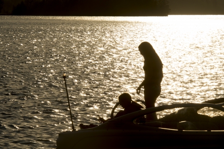Silhouette of two people on a motorboat at sunset, Lake of The Woods, Keewatin, Ontario, Canadaの写真素材