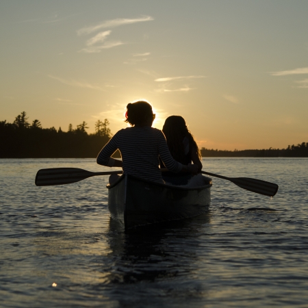 Woman rowing a boat with her daughter at sunset, Lake of The Woods, Keewatin, Ontario, Canadaの写真素材