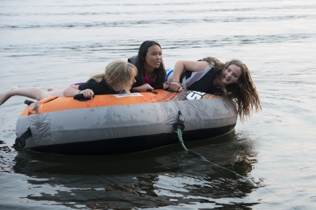Three girls enjoying on inflatable raft in the lake, Lake Of The Woods, Keewatin, Ontario, Canadaの写真素材