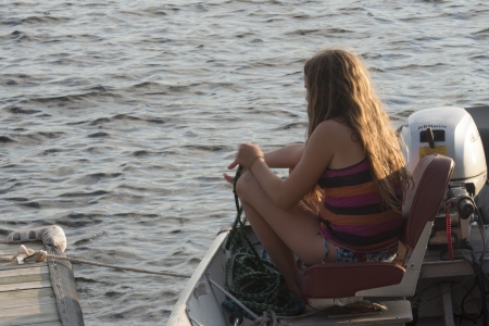 Girl sitting on a motorboat in a lake, Lake of The Woods, Keewatin, Ontario, Canadaのeditorial素材