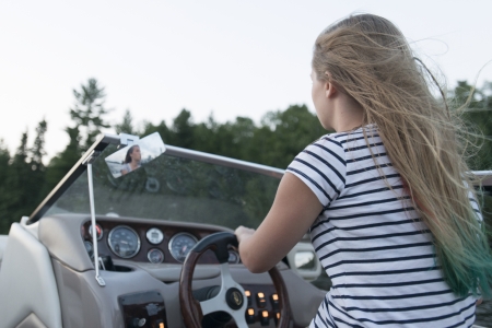 Girl driving a motorboat, Lake of The Woods, Keewatin, Ontario, Canadaの写真素材