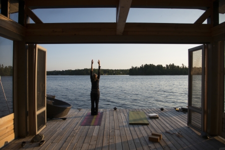 Rear view of a person practicing yoga on a pier, Lake of The Woods, Ontario, Canada