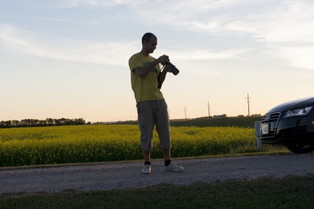 Photographer standing on the road and adjusting his camera, Manitoba, Canadaのeditorial素材