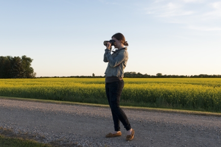 Woman standing on the road photographing with a digital camera, Manitoba, Canadaのeditorial素材
