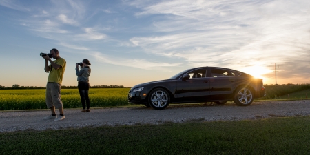Young couple taking pictures along a prairie road, Manitoba, Canada