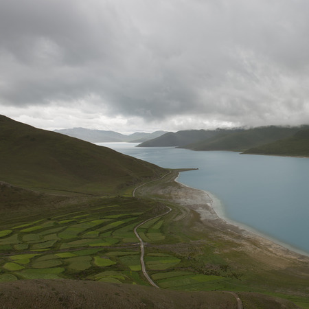 Aerial view of road passing through agricultural fields along Yamdrok Lake, Nagarze, Shannan, Tibet, Chinaの写真素材