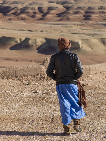 Tuareg man looking at a town view from the terrace of a fort, Ait Benhaddou, Ouarzazate, Souss-Massa-Draa, Moroccoの写真素材