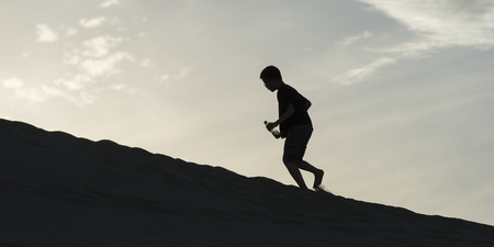 Person climbing on sand dune at Mingsha Shan, Dunhuang, Jiuquan, Gansu Province, Chinaの写真素材
