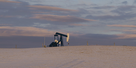 Oil well in snow covered field, Cowboy Trail, Alberta Highway 22, Alberta, Canadaの写真素材