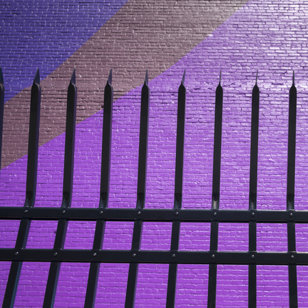 Metal fence by colorful wall, Minneapolis, Hennepin County, Minnesota, USAの写真素材