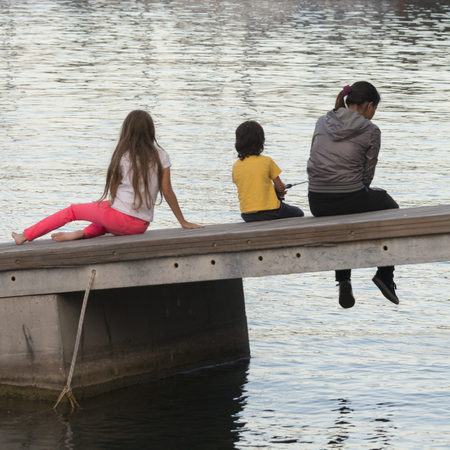 Children sitting on jetty, Sant'Angelo, Ischia Island, Campania, Italyの写真素材