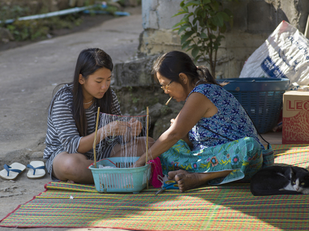 Teenage girl with a woman making craft products, Chiang Rai, Thailandのeditorial素材
