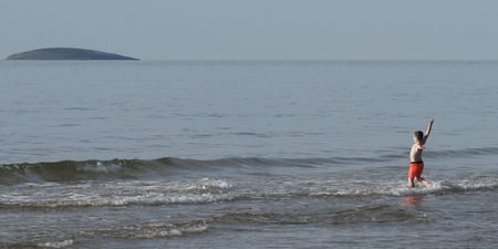 Boy with arms outstretched in the ocean, Inverness Beach, Mabou, Cape Breton Island, Nova Scotia, Canadaのeditorial素材
