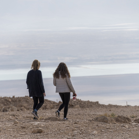 Rear view of two teenage girls walking in desert, Masada, Judean Desert, Dead Sea Region, Israel