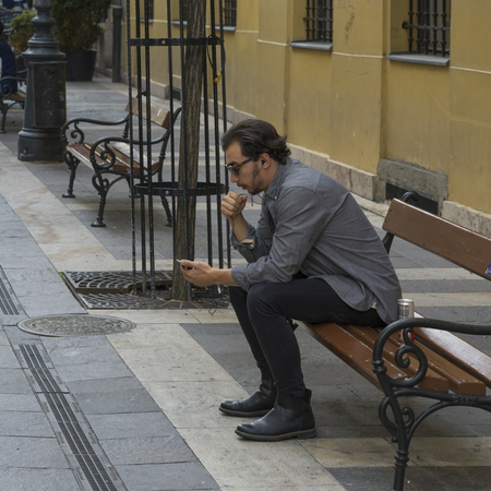 Man sitting on bench using a cell phone, Budapest, Hungaryのeditorial素材