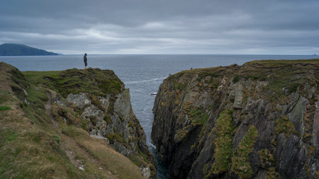 Person standing on cliff, Achill Island, County Mayo, Irelandのeditorial素材