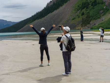 Tourists photographing at lakeside, Lake Louise, Improvement District 9, Banff National Park, Alberta, Canadaのeditorial素材