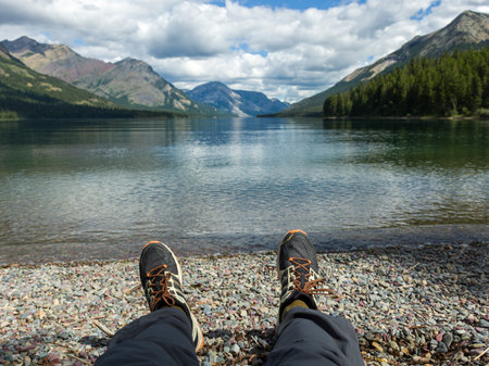 View of a person's feet with a lake and mountain range in the background, Waterton Lake, Waterton-Glacier International Peace Park, Waterton Lakes National Park, Alberta, Canadaのeditorial素材