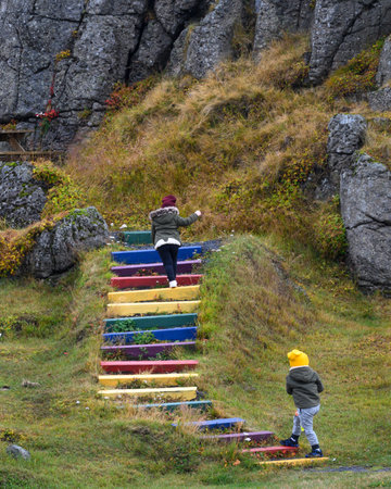 Tourists walking up colorful steps at mountainside, Holmavik, strandabyggd, Westfjords, Iceland