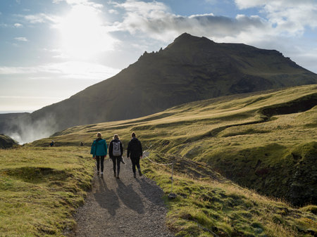 Tourists walking on path with waterfall in the background, Skogafoss Waterfalls, Rangarthing Eystra, Southern Region, Icelandのeditorial素材