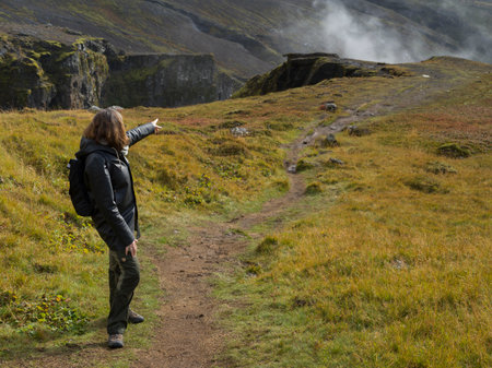 Female hiker pointing towards Glymur Waterfall, Glymur Hiking Trail, Hvalfjaroarsveit, Capital Region, Icelandのeditorial素材