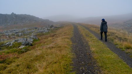 Woman walking on foggy trail, Strandabyggd, Westfjords, Icelandのeditorial素材