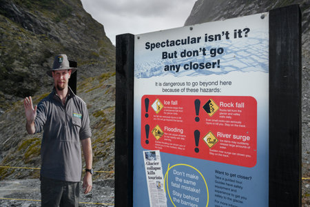 Security official standing next to warning sign, Franz Josef Glacier walk, Westland National Park, South Island, New Zealandのeditorial素材