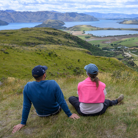 Tourists sitting on a hilltop looking at view, Diamond Lake Conservation Area, Diamond Lake, Lake Wanaka, South Island, New Zealandのeditorial素材