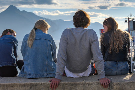 Friends sitting on edge of a wall, Queenstown, South Island, New Zealandのeditorial素材