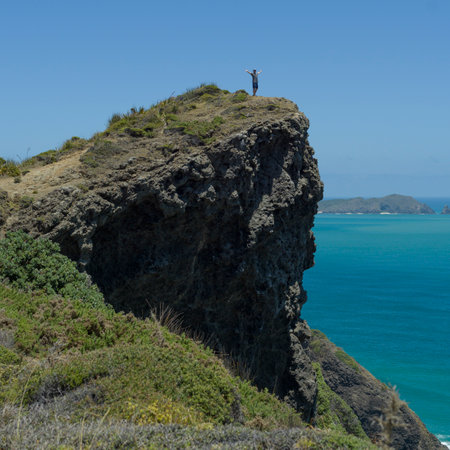 Man standing on tip of a rocky cliff, North Easternmost Tip, Aupouri Peninsula, Cape Reinga, North Island, New Zealandのeditorial素材