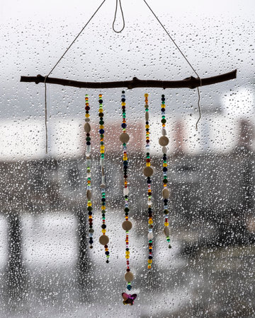 Rows of beads suspended from a twig in front of a rain splashed window, Village of Alert Bay, Cormorant Island, British Columbia, Vancouver Island, Canadaのeditorial素材