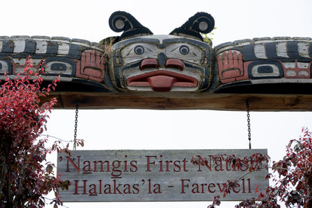Namgis First Nations sign below an Indigenous carving on Alert Bay on Cormorant Island, Johnstone Strait, British Columbia, Vancouver Island, Canadaのeditorial素材